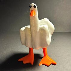 a white duck with an orange beak standing on a table next to a gray background