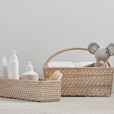 an elephant toy sitting in a basket next to some bottles and soaps on a table