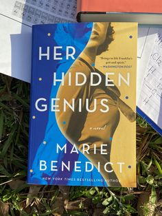 the book her hidden genius by marie benedict is laying in the grass