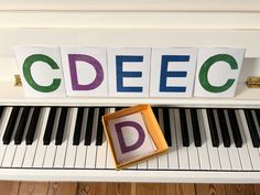 a box sitting on top of a piano with the letters d and c spelled in blocks