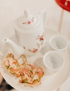 a tea set on a white plate with pink flowers