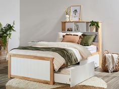 a bedroom with a bed, dresser and plant on the floor in front of it