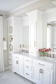 a bathroom with two sinks and white cabinets