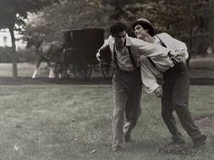 an old photo of two men playing frisbee in the grass with a horse and buggy behind them