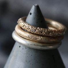 three gold rings stacked on top of each other with a black cone in the background