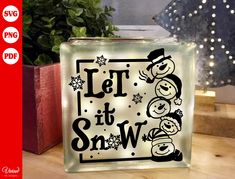 a glass block with the words let it snow in black and white lettering on it