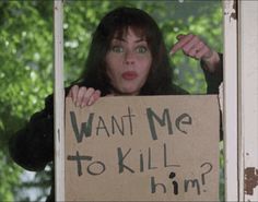 a woman holding a sign that says want me to kill him