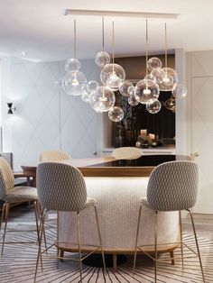 a modern kitchen with an island and marble counter tops, hanging lights over the dining room table