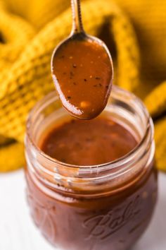 a spoon full of sauce on top of a jar