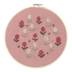 a pink embroidery kit with white and pink flowers on the front, in an embroidered hoop