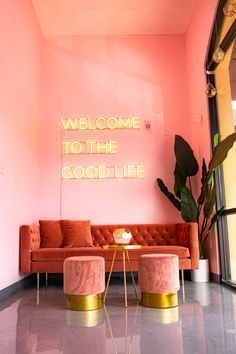 a living room with pink walls and gold trimmings on the wall is decorated with neon lights