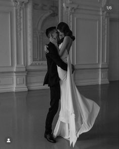 black and white photo of bride and groom dancing in an empty room with high ceilings