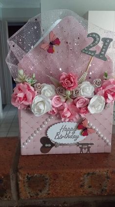 a pink birthday card with flowers and butterflies on it, sitting on a brick wall