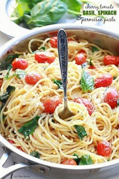 a pasta dish with tomatoes and spinach in a pan