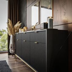 a black sideboard with gold handles and drawers in a room that has wood floors