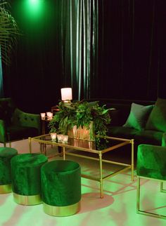 a living room with green velvet furniture and candles on the coffee table in front of it