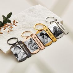 four keychains with different pictures on them sitting next to a plant in a vase