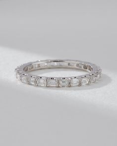 a white gold ring with baguets and diamonds on it, sitting on a table