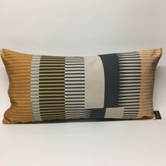 a pillow that is sitting on top of a white table next to a black and yellow striped pillow