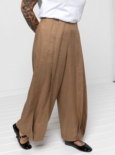 a woman in white shirt and khaki pants with tattoos on her arm standing