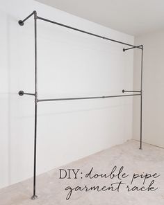 an empty room with white walls and black metal pipe work on the wall, along with text that reads diy double pipe garment rack