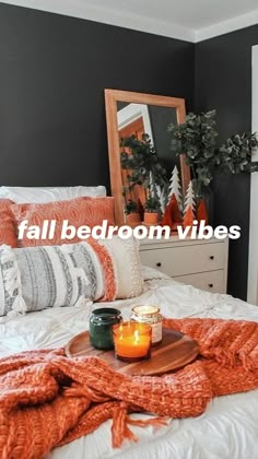 an orange blanket is on top of a bed next to candles and potted plants