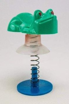 a green frog sitting on top of a blue stand with its head turned to the side