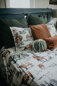 a bed with many pillows on it and a cactus in the corner next to it