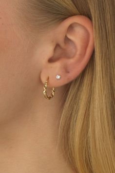 a close up of a woman's ear wearing a pair of gold hoop earrings