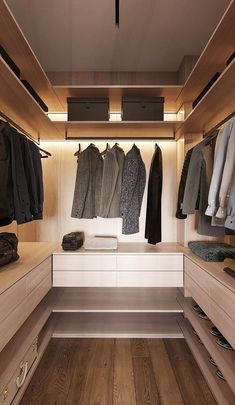 a walk in closet with clothes hanging on the wall and wooden flooring that is lit by recessed lighting