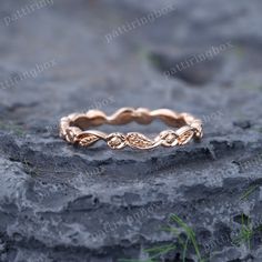 a rose gold wedding band on top of a rock