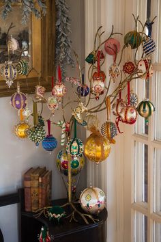 a christmas tree with ornaments hanging from it's branches in front of a window