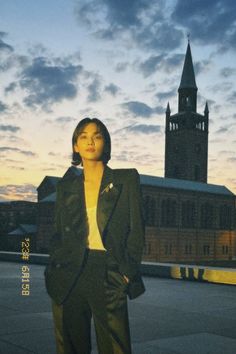 a woman standing in front of a building at sunset