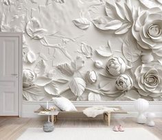 a white room with flowers on the wall and a bench in front of it,