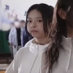 a woman with long hair standing in front of a group of people wearing white sweatshirts