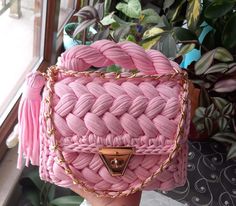 a pink handbag sitting on top of a table next to a potted plant