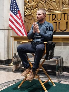 a man is sitting in a chair with an american flag on the floor behind him