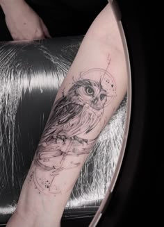 an owl tattoo on the leg of a woman's arm, with space and stars around it