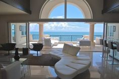 a living room filled with white furniture and large windows