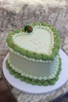 a heart shaped cake with green frosting and gold decorations