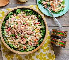 a salad with meat and vegetables in a wooden bowl on a table next to three forks