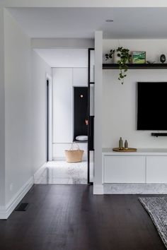 a flat screen tv sitting on top of a white wall mounted shelf next to a wooden floor