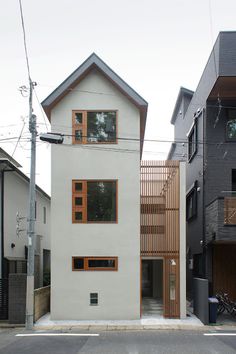 the house is white and has brown trim on the windows, along with wooden slatted balconies