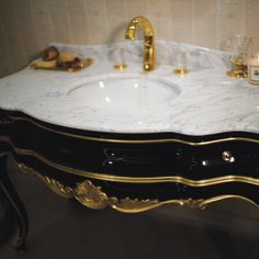 a bathroom vanity with marble top and gold trim