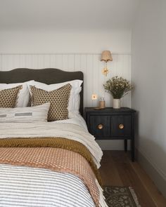 a bed with white and brown pillows in a bedroom next to a black night stand