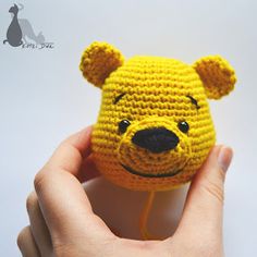 a crocheted winnie the pooh head is held in someone's hand