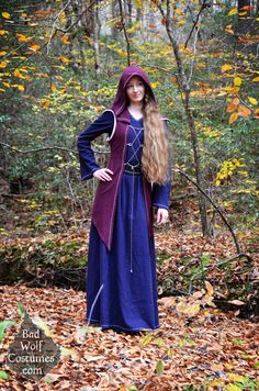 a woman dressed in medieval clothing standing in the woods with her hands on her hips