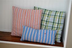 three pillows are sitting on a shelf in the corner