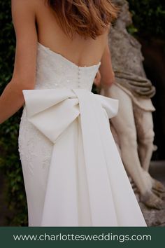 a woman in a white dress with a big bow on her back