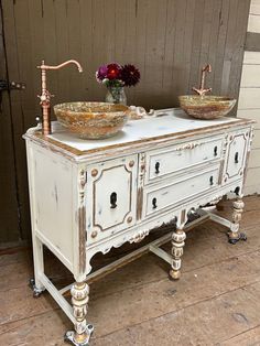 two bowls are sitting on top of an old white cabinet with gold trimmings